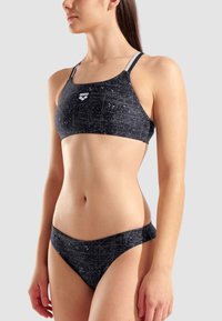 Zwart en grijs tweedelig bikini met een geometrisch patroon, voorzien van een sportieve top met dunne bandjes en een laag gesneden broekje.