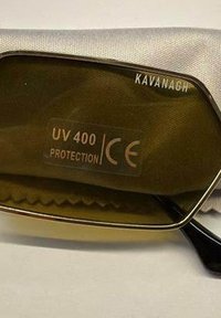 Šošovka slnečných okuliarov s nálepkou "UV 400 ochrana" a značkou CE, názov značky "Kavanagh" na okraji rámu.