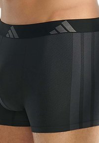 Čierne atletické boxerky s textúrovaným povrchom, s širokým elastickým pásom s nenápadným vzorom troch pruhov.