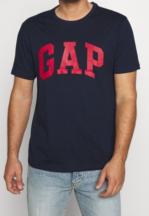 Granatowa bawełniana koszulka z krótkim rękawem z wyraźnym czerwonym napisem "GAP" na piersi. Gładka tekstura, klasyczny okrągły dekolt.