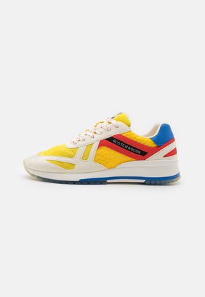 Żółty, biały, czerwony i niebieski sneaker z logo Scotch & Soda po boku i białymi sznurówkami, pokazany z profilu na białym tle.