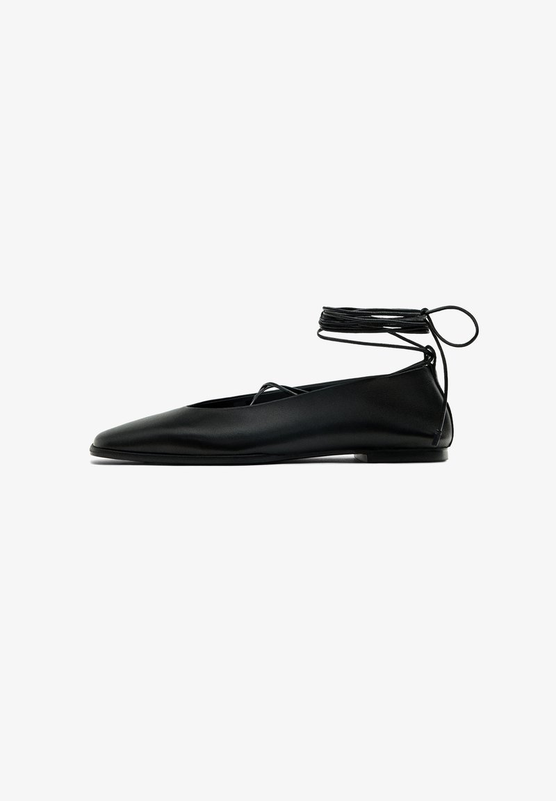 Ballerine plate noire en cuir lisse avec bout pointu, design en V ouvert et lacets enveloppants autour de la cheville.