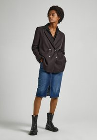 Double-breasted dark jacket with a black collar, paired with a mid-length denim skirt and black ankle boots featuring chunky soles.