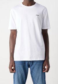 Wit katoenen T-shirt met korte mouwen en een ronde hals. Voorzien van een klein zwart "HUGO"-logo op de linkerborst. Eenvoudig ontwerp.