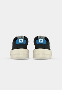Sneaker nere in tela con suola in gomma crema, caratterizzate da un accento blu a forma di stella sul tallone e il marchio in rilievo "CONVERSE ALL STAR".