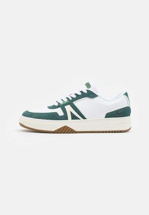 Zapatilla blanca con acentos de gamuza verde, suela de goma texturizada y un destacado elemento de diseño en forma de A en color crema. Incluye cordones y un collar acolchado.
