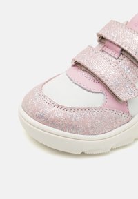 Baskets roses avec un dessus pailleté et des accents blancs, fermetures Velcro et bout arrondi. Semelle en caoutchouc avec une texture antidérapante.