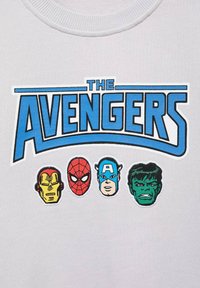 Biela mikina s textom "THE AVENGERS" v modrej farbe, s vyobrazením štyroch hláv postáv: Iron Man, Spider-Man, Captain America a Hulk v farbe.