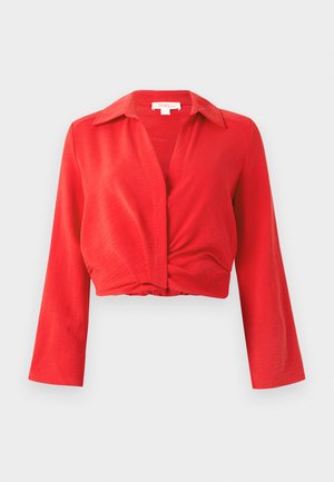 Bluză roșie scurtă cu guler tăiat, mâneci lungi și detaliu întors în față. Fabricată dintr-un material ușor, texturat.