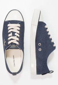 Jeansneakers med krämfärgad gummikåpa och sula, snörning och beige snören. Har metallöglor och logotyp på sidan.