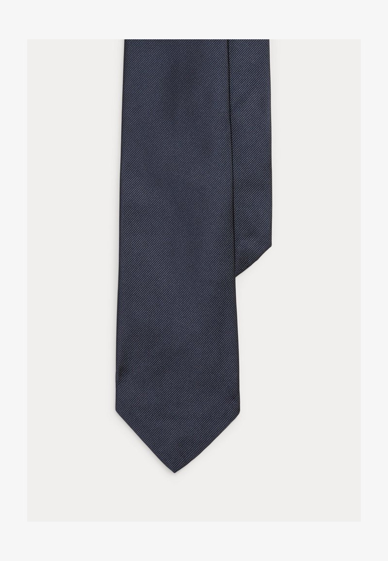 Γραβάτα σε ναυτικό μπλε χρώμα, κατασκευασμένη από υφασμάτινη υφή, με διαγώνιο σχέδιο ψαροκόκκαλου και μυτερή άκρη. Πρότυπο λεπτό σχήμα, λεία επιφάνεια.