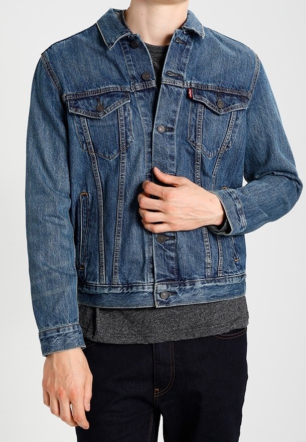 Modrá džínová bunda s dvěma náprsními kapsami, zapínáním na knoflíky a límcem. Látka má klasickou texturovanou úpravu a mírně vybledlý vzhled.