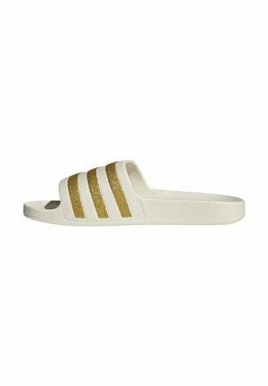 Witte slidesandaal met een gestructureerde zool en vier gouden glitterstrepen over het bovenste bandje, zijaanzicht op een witte achtergrond.
