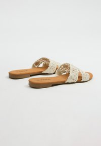 Sandalias de punta abierta con un upper de encaje beige, plantilla de ante marrón sintético y suela plana con un diseño simple y sin adornos.