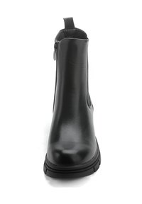Botín negro de cuero liso con punta redonda, cremallera lateral y suela baja de goma. Cuenta con una lengüeta en la parte trasera.
