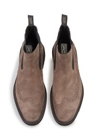 Botas Chelsea de ante marrón con paneles laterales elásticos, detalles de brogue en la parte superior y una suela de goma negra resistente.