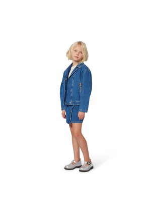 Giacca di jeans con bottoni anteriori e due tasche laterali, abbinata a pantaloni corti di jeans e scarpe grigie con dettagli a fibbia.