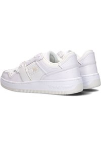 Baskets blanches avec un mélange de cuir lisse et texturé, un design low-top, un col rembourré et un branding subtil sur le talon.