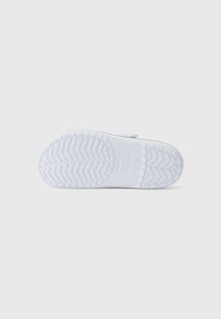 White rubber shoe sole with a textured zigzag pattern, featuring the word "CROCS" embossed near the heel and a smooth edge.