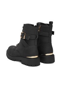 Czarne botki za kostkę o teksturowanym wykończeniu, z detalami w postaci złotej klamry i srebrnych akcentów. Posiadają solidną gumową podeszwę i zamek błyskawiczny z boku.