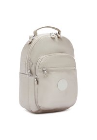 Zaino in nylon beige con forma arrotondata, due scomparti con zip, maniglia superiore e una toppa circolare con logo sulla parte anteriore. Accessori in metallo argentato.