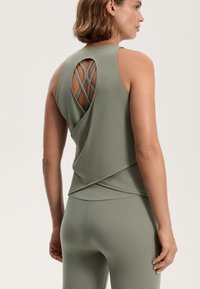 Sleeveless, olive green athletic top with a unique crossover design and crisscross back detail. Made of smooth, stretchy fabric.