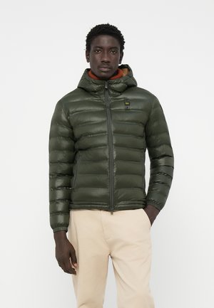 Padded green jacket with a zippered front and attached hood, featuring a smooth texture and elastic cuffs, paired with light trousers.