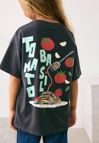 Černé bavlněné tričko s barevnými grafikami rajčat, česneku a těstovin, se slovy "Rajče Bazalka" v tučných písmenech.