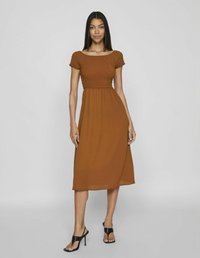 Rochie maronie de lungime medie, cu un bust elastic și mâneci scurte, fustă fluidă și o textură moale; asociată cu tocuri negre cu curele.