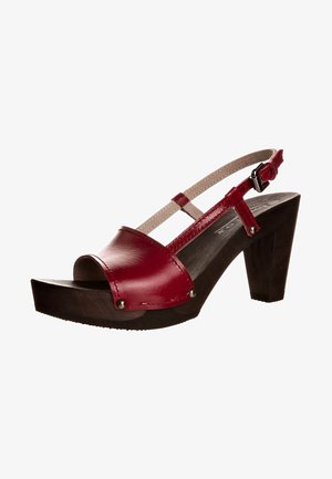 Sandalia roja de cuero con punta abierta, tacón de plataforma de madera y correa ajustable beige en el tobillo con hebilla.