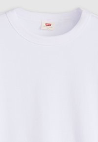T-shirt en coton blanc avec un col rond et une texture douce. Présente une petite étiquette rouge Levi's à l'intérieur du col.