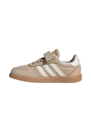 Sneaker in camoscio beige con tre strisce bianche, suola in gomma color cuoio, lacci e una fascia in velcro sulla parte superiore.