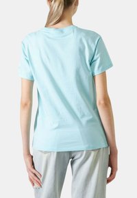 T-shirt di cotone azzurro chiaro con maniche corte. Presenta un taglio semplice e classico con scollatura rotonda. Superficie liscia, senza motivi visibili.