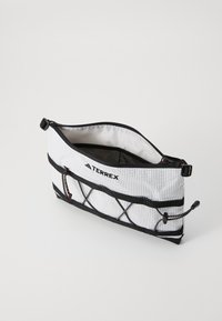 Sac de mână alb cu fermoar și accente negre, panou din plasă și cordon ajustabil. Prezintă logo-ul "TERREX" pe față și un interior neted.