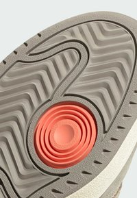 Potplat cipela od sive teksturirane gume, s spiralnim koraljnim akcentom i cik-cak uzorkom za bolje prianjanje i potporu.