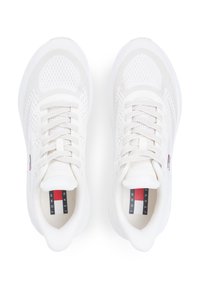 Λευκά αθλητικά παπούτσια με πλέγμα διαθέτουν υφή στο πάνω μέρος, στρογγυλή μύτη και επίπεδα κορδόνια. Διακριτικό λογότυπο στη γλώσσα σε κόκκινο, λευκό και μπλε χρώμα.