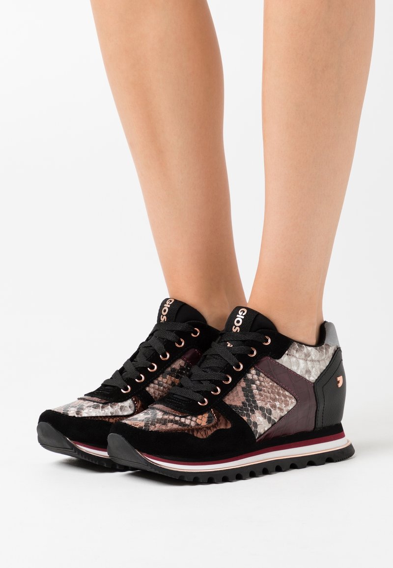 Sneakers nere e metalliche con motivo a pelle di serpente testurizzata. Presentano un design con zeppa, materiali a contrasto e dettagli in oro rosa.