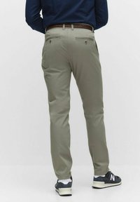 Ljus khaki-byxor med slim fit, med bakfickor och ett vävt brunt bälte. Kombineras med mörka sneakers för en avslappnad look.