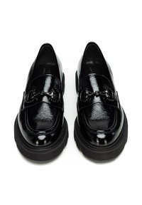 Mocassini in pelle verniciata nera con suola spessa nera, caratterizzati da elementi decorativi sulla parte superiore e una finitura liscia e lucida.