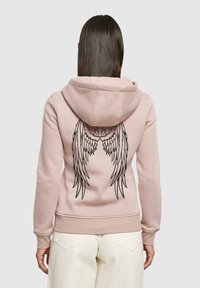 Felpa rosa con un grande grafismo di un'ala nera sul retro, realizzata in un morbido tessuto con cappuccio regolabile e polsini a costine.