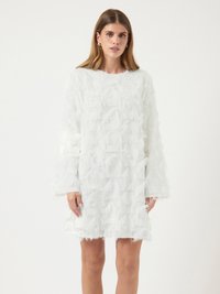 Robe blanche à manches longues, avec des franges superposées pour la texture. Longueur au-dessus du genou avec une silhouette droite et un col rond.