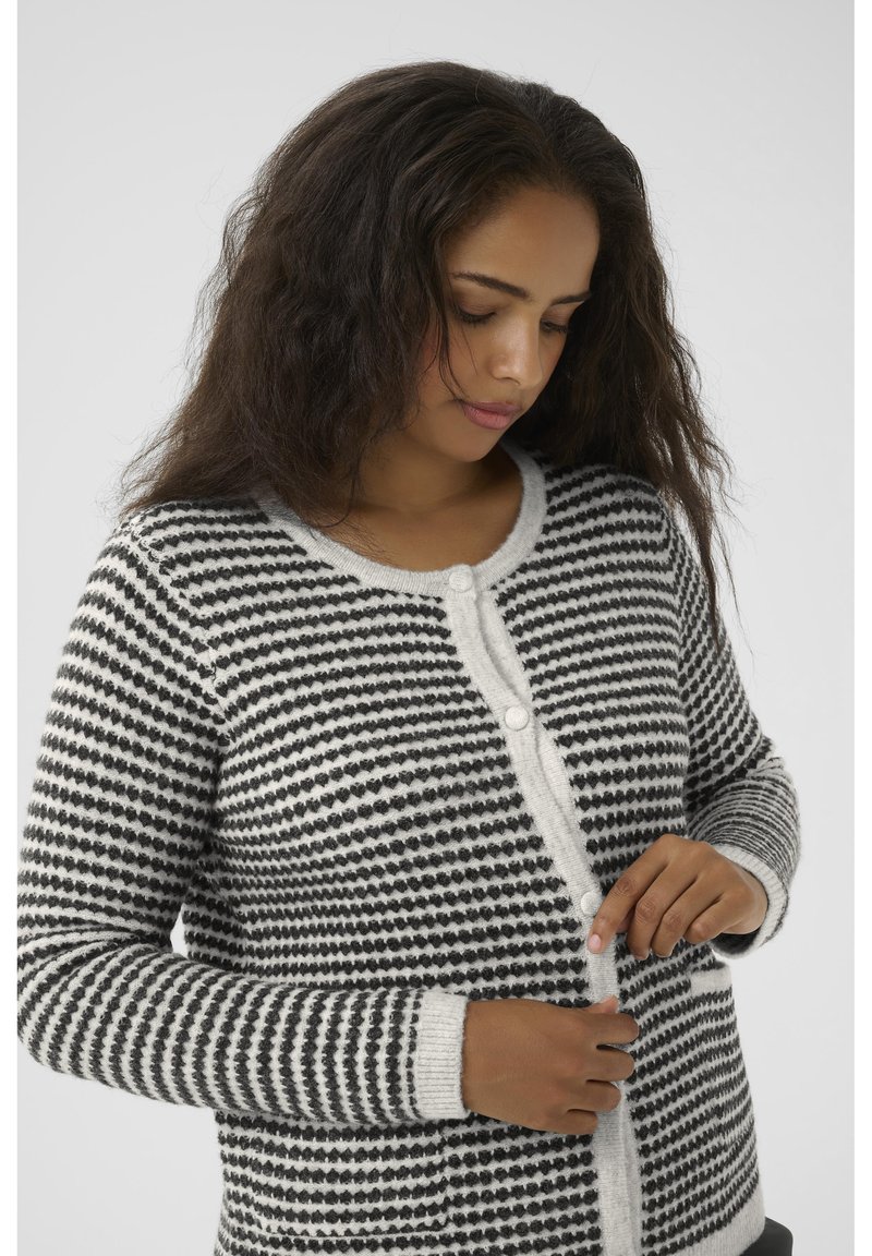 Black and white striped cardigan featuring a round neckline, button front, and textured knit pattern. Long sleeves with ribbed cuffs.