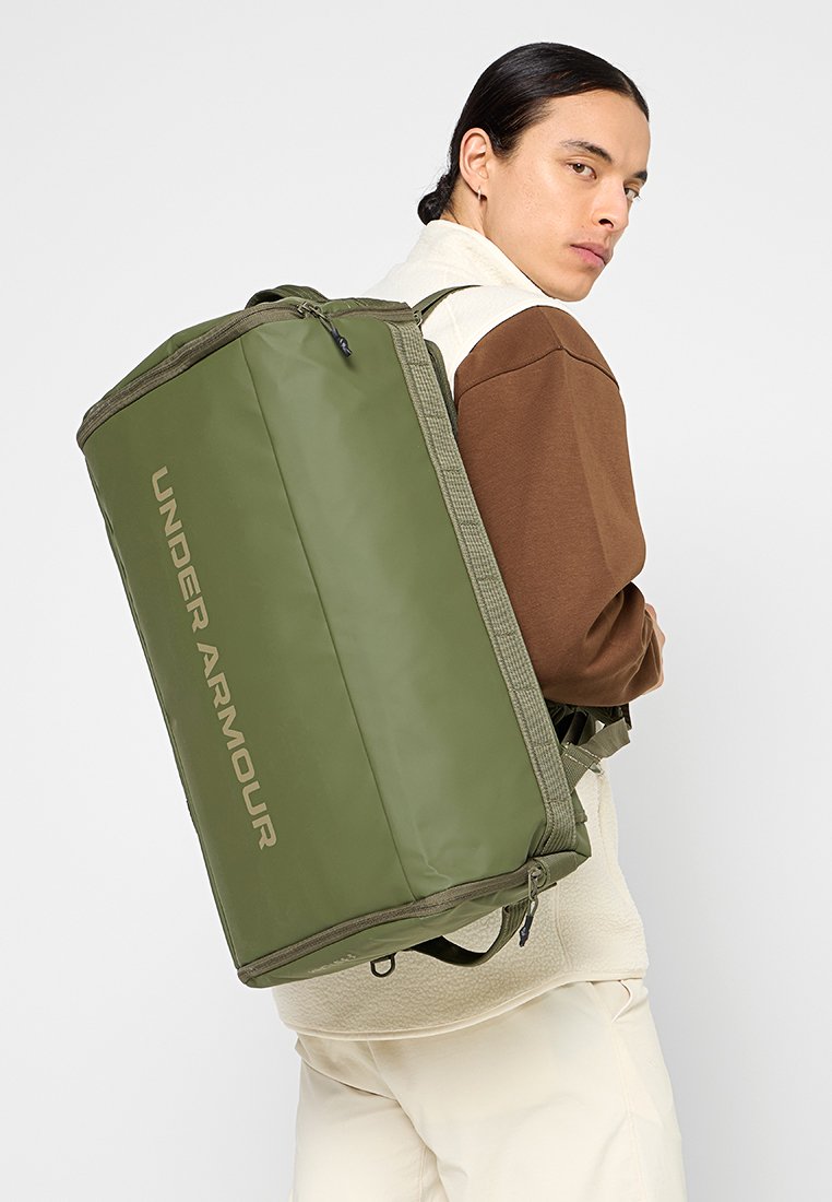 Grüner Under Armour Rucksack mit rechteckigem Design, strukturiertem Stoff, seitlichem Reißverschluss und Logo auf der Vorderseite. Verstellbare Riemen.