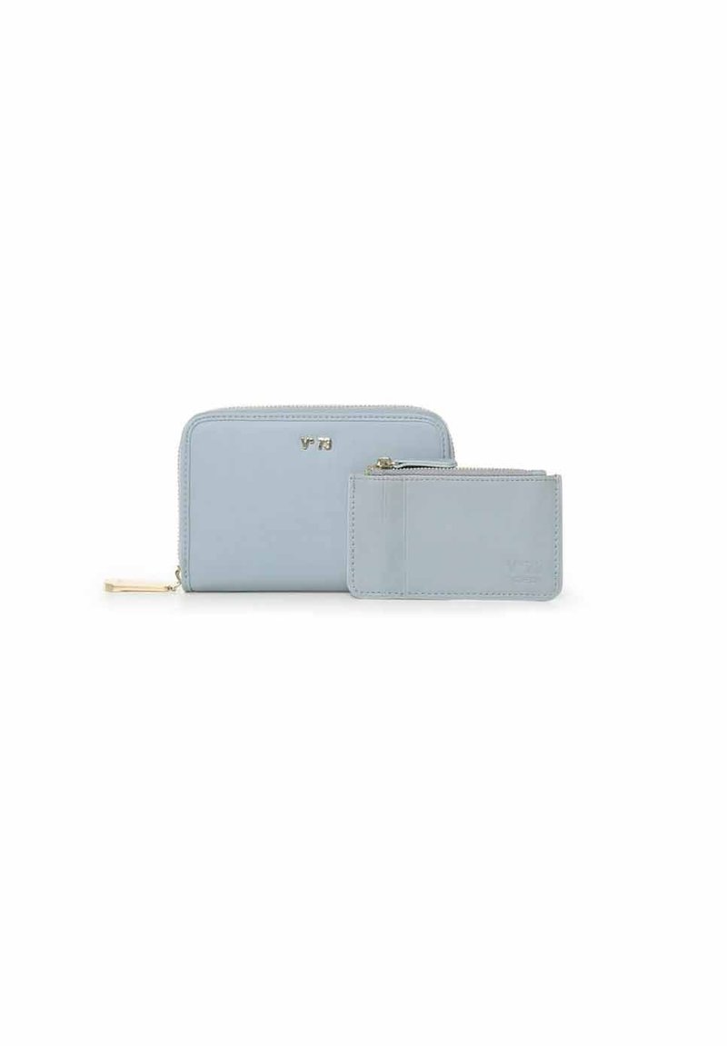 Conjunto de cartera de cuero azul claro, con una cartera principal con cremallera y un tarjetero más pequeño. Ambos tienen texturas suaves y sutiles acentos dorados.