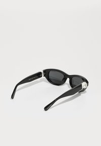 Schwarze Sonnenbrille mit einem eleganten Design, dunkeltönenden Gläsern und dekorativen Kristallakzenten an den Bügeln. Glänzende Oberfläche, leichter Kunststoffrahmen.