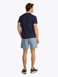 Marine bluse i bomull med korte ermer, kombinert med lyseblå shortser. Modellen har på seg mørke joggesko med hvite såler. Enkel, uformell design.