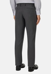 Grå skräddarsydda byxor med en jämn textur, slim-fit design, raka ben och sidofickor, tillsammans med svarta skor.