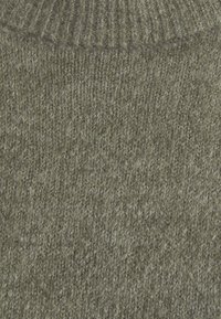 Grüner gestrickter Pulloverstoff mit einem strukturierten Rippenmuster, hergestellt aus weichem Material mit einer leicht flauschigen Oberfläche.