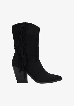 Bota de cowboy de ante negro con punta afilada, tacón apilado y detalle de flecos verticales en la parte trasera. Textura suave y diseño estructurado.