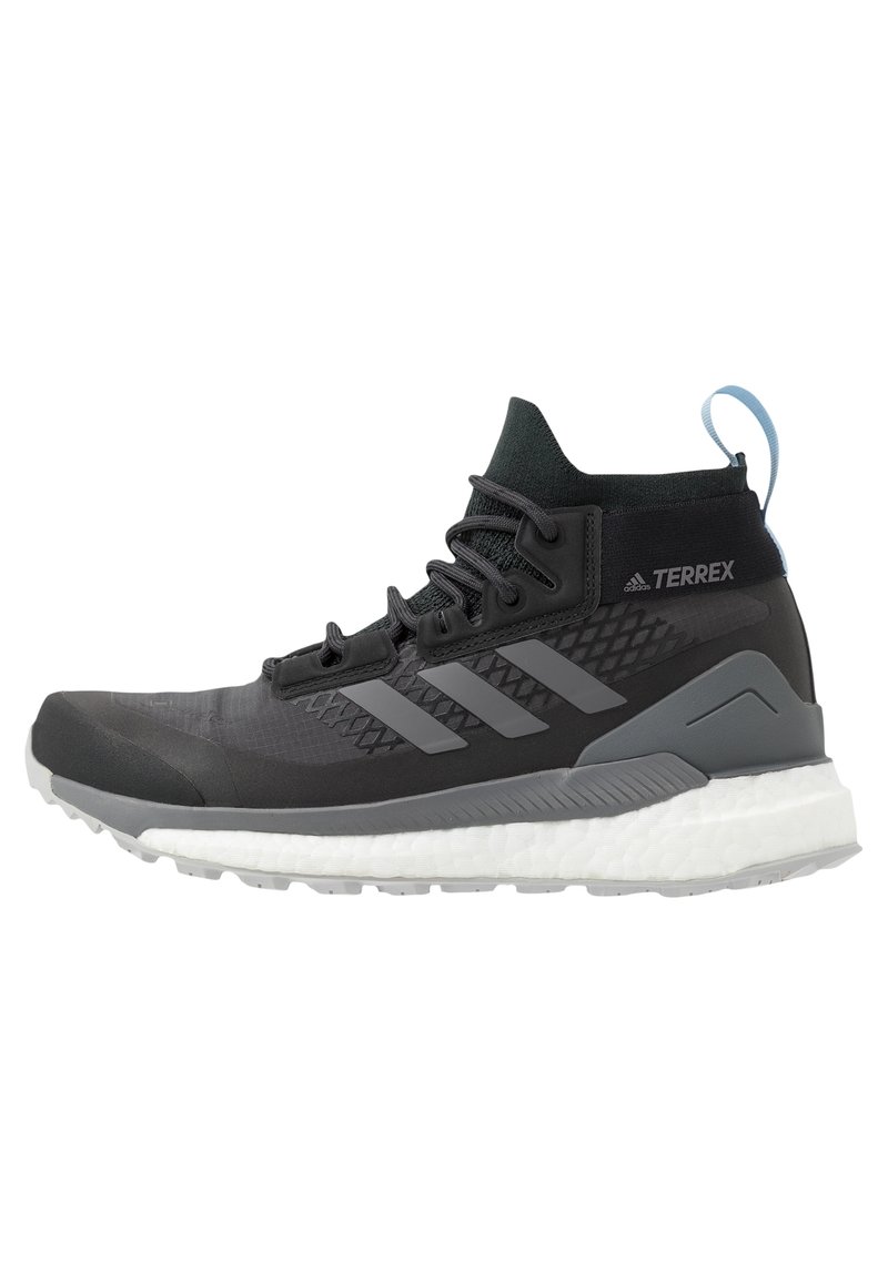 Zapatilla alta Adidas Terrex en negro y gris, con cuello de tobillo tipo calcetín, cordones, tres franjas en el lateral y suela blanca acolchada.